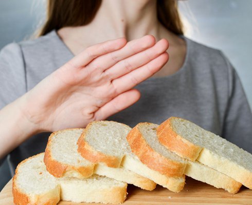 Gluten intolerance concept. Young girl refuses to eat white bread - shallow depth of field - selective focus on bread; blog: common signs of celiac disease