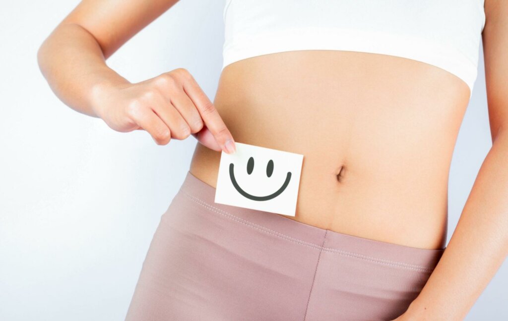 a happy face over a woman's stomach to symbolize why to improve your gut health