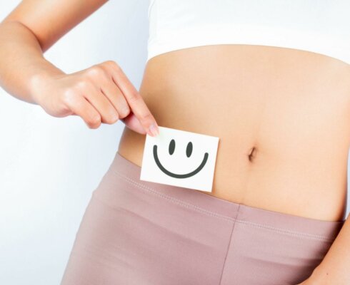 a happy face over a woman's stomach to symbolize why to improve your gut health
