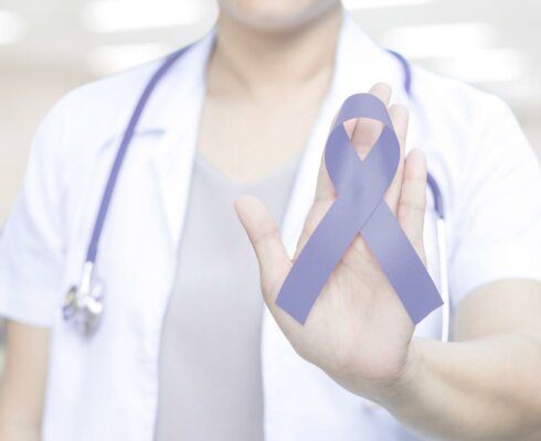 A healthcare worker holding a purple awareness ribbon to represent the risk factors for stomach cancer