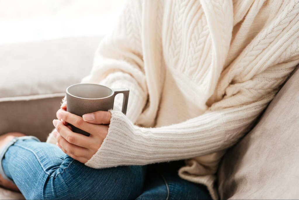 A woman wearing a sweater holding a warm cup of tea to represent wintertime tips for gastrointestinal health