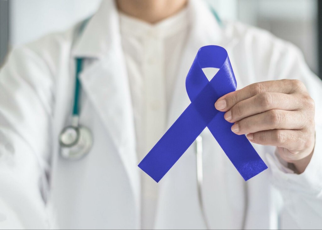 A physician holding a blue ribbon to represent colorectal awareness month and the facts you need to know about colorectal cancer