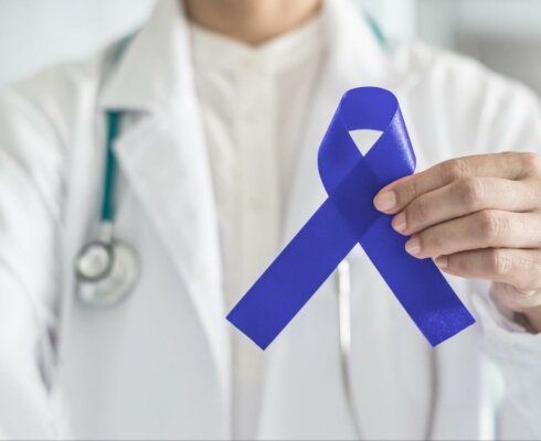 A physician holding a blue ribbon to represent colorectal awareness month and the facts you need to know about colorectal cancer